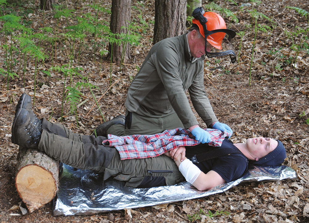 Forestry worker giving First Aid to a casualty on the forest floor